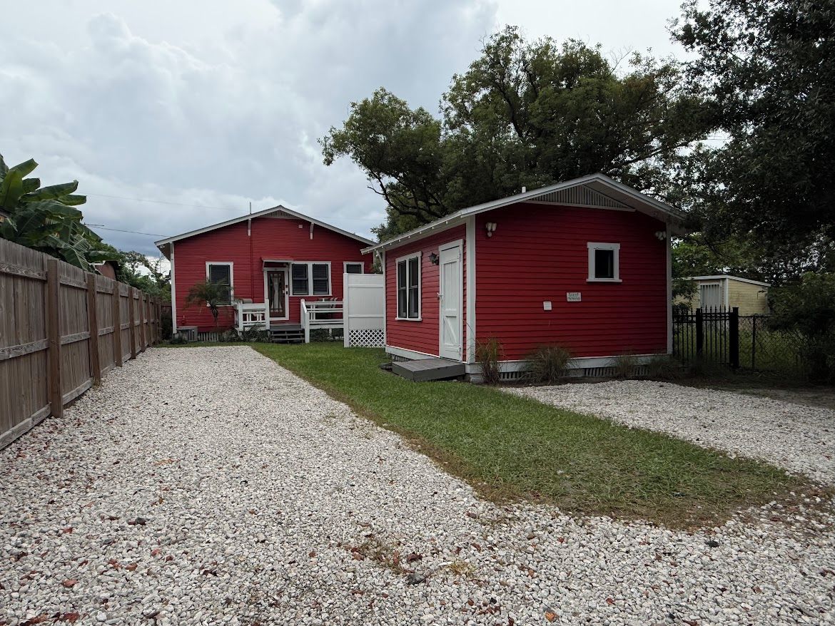 Un bâtiment rouge avec une allée gravillonnée et une clôture en bois.