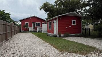 Un bâtiment rouge avec une allée gravillonnée et une clôture en bois.