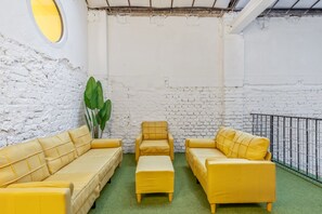 A room with a white brick wall, a round window, and yellow furniture. - Quiet Studio Facing the Courtyard | Karmelitermarkt | Self-Check-In (Wien)