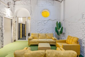 A room with a white brick wall, a round yellow window, and a yellow sofa set. - Quiet studio overlooking the courtyard | Karmelitermarkt | Self-check-in (Wien)