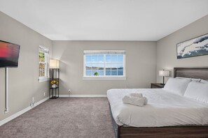 A bedroom with a bed, a TV, a window with a view, and a lamp. - Lagoonfront 3BR Pickleball, Kayaks, Basketball (Carlsbad)