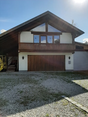 A two-story house with a garage, a covered porch, and a gravel driveway.