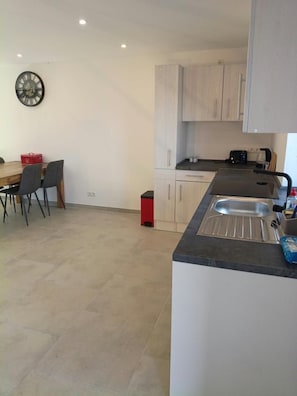 A kitchen with a sink, cabinets, and a dining area with chairs and a table. - New! Meerzeit Vacation Home (Nenndorf)