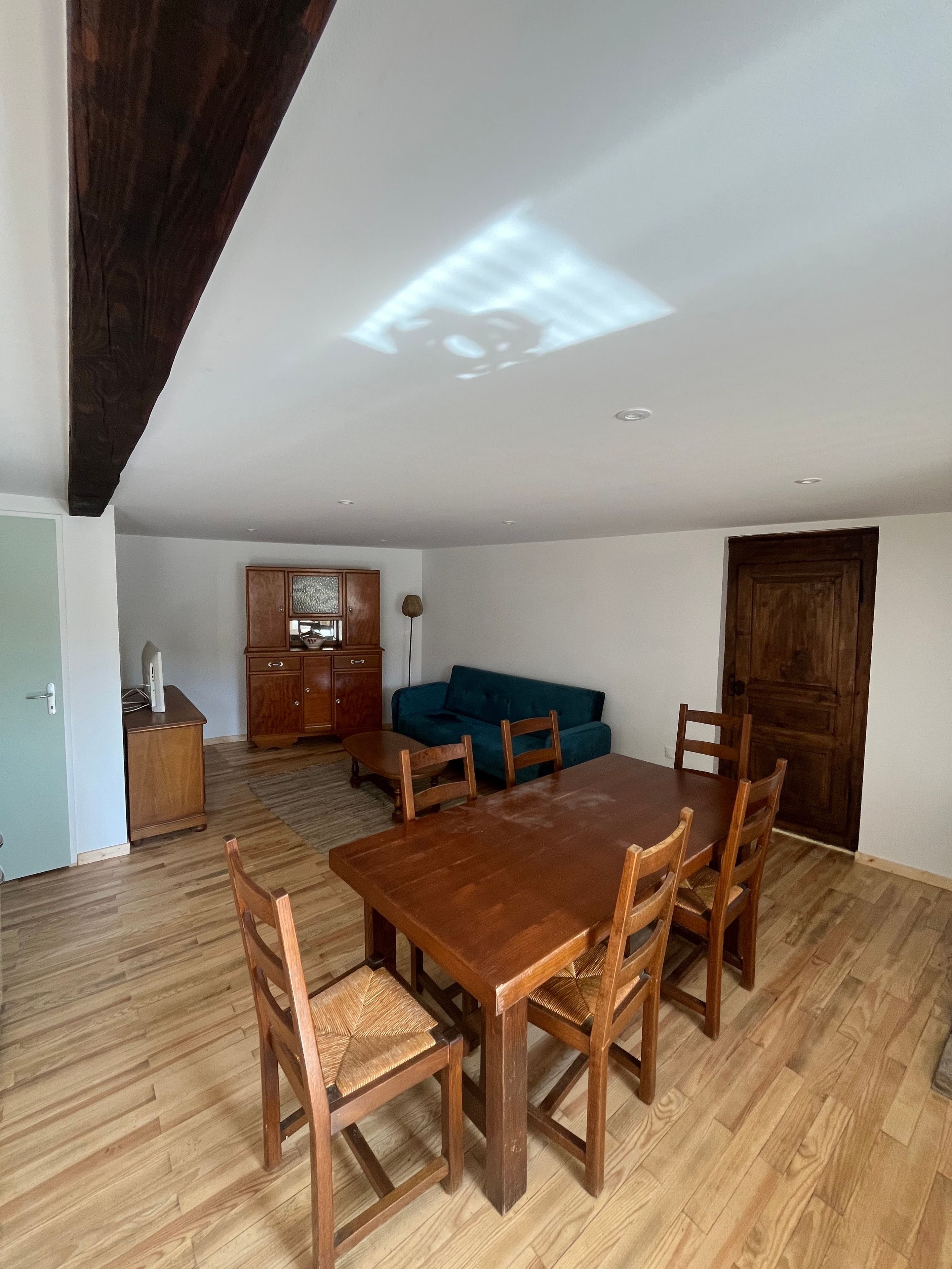 Un coin repas avec une table et des chaises en bois, un canapé et un meuble.