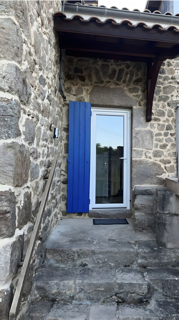 A stone building with a blue door and a small porch area.