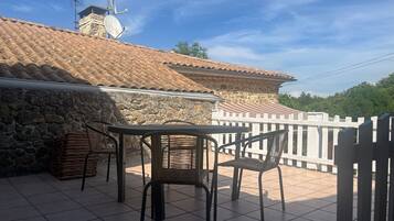A terrace with a tiled floor, a stone wall, and a white fence.