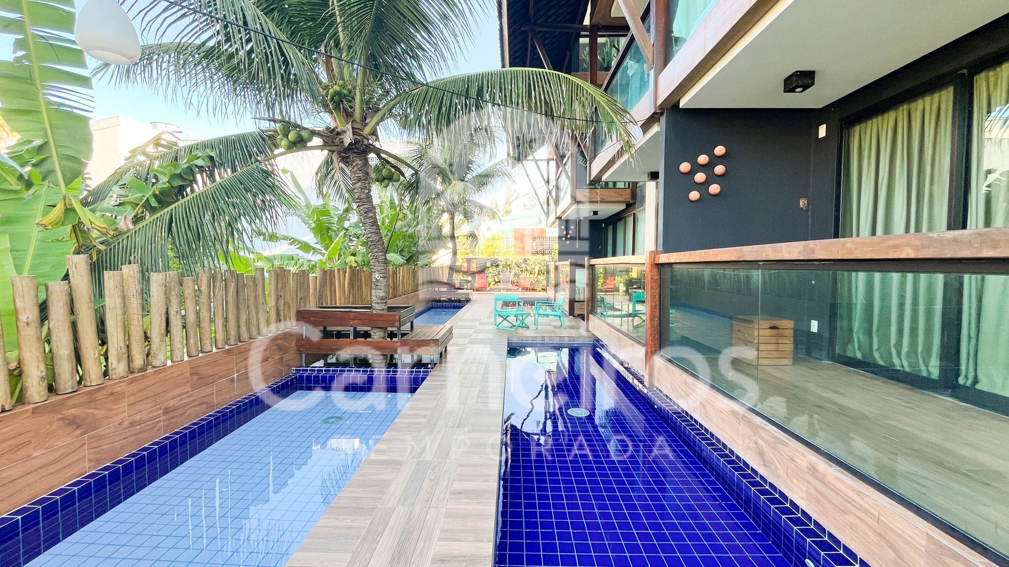 Une piscine aux carreaux bleus, avec une terrasse en bois et une clôture en bois.