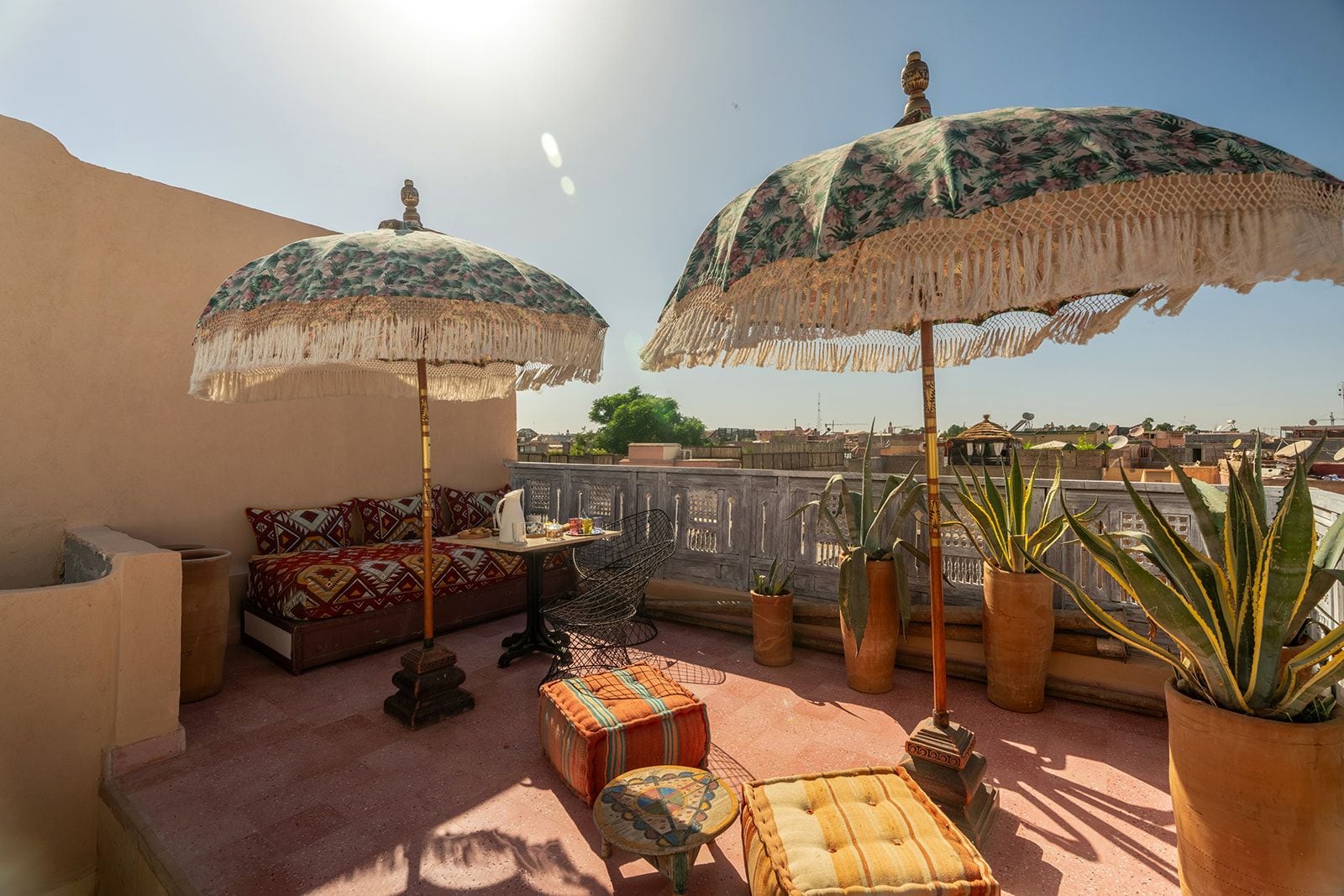 Une terrasse sur le toit, avec un canapé, deux parasols, des plantes en pot et une vue sur le paysage urbain.