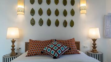 A bed with patterned pillows, two bedside lamps, and decorative wall art.
