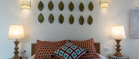 A bed with patterned pillows, two bedside lamps, and decorative wall art.