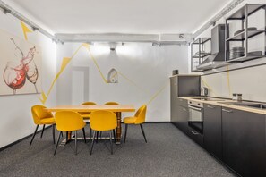 A modern kitchen with a dining area, featuring a wooden table and yellow chairs, and a black countertop with a sink. - 2 bedrooms with a terrace | Karmelitermarkt | 6 guests (Wien)