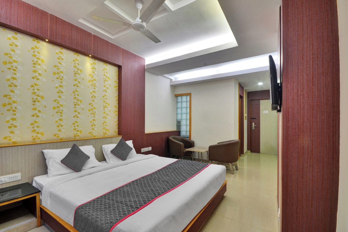 A hotel room with a bed, a desk, a chair, a television, and a ceiling fan.