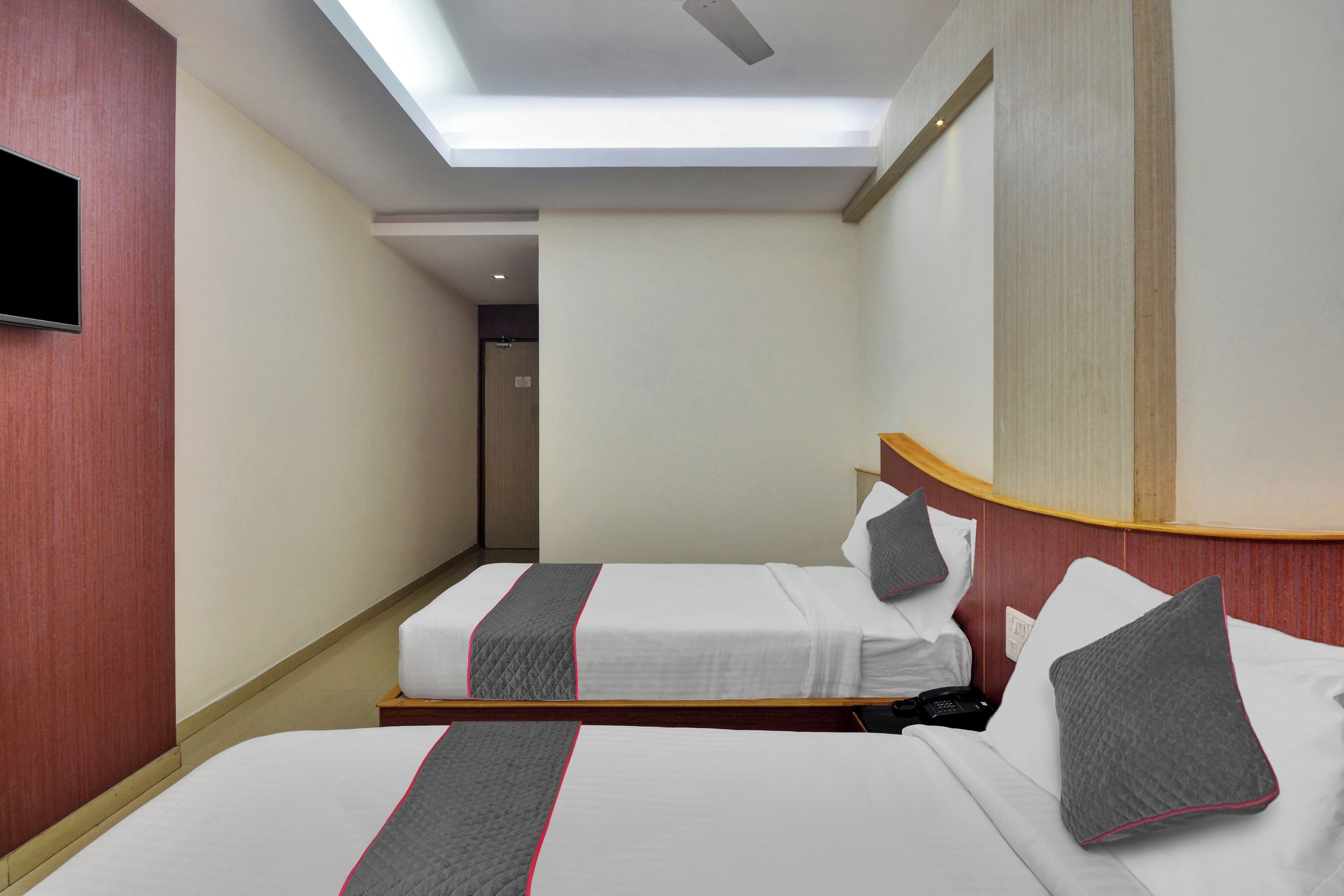 Una habitación de hotel con dos camas, un televisor en la pared y una lámpara en el techo.