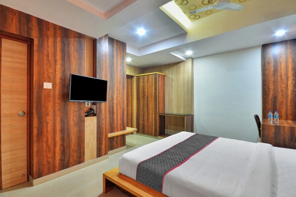 Quarto de hotel com cama, televisão, guarda-roupa e zona de duche.