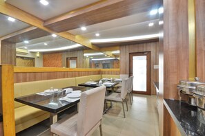 Un restaurante con cabinas y mesas, paneles de madera y piso de baldosas.