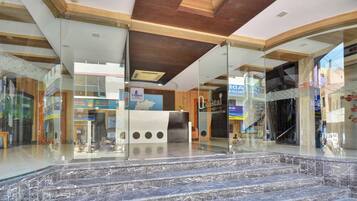 Un vestíbulo de hotel con escalones de mármol, paredes de vidrio y techo de madera.