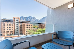 A balcony with two chairs and a view of buildings and mountains. - Newlands Peak Studio with AC and gym (Cape Town)