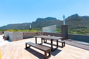 An outdoor patio with a table and benches, overlooking a mountainous landscape. - Newlands Peak Studio with AC and gym (Cape Town)