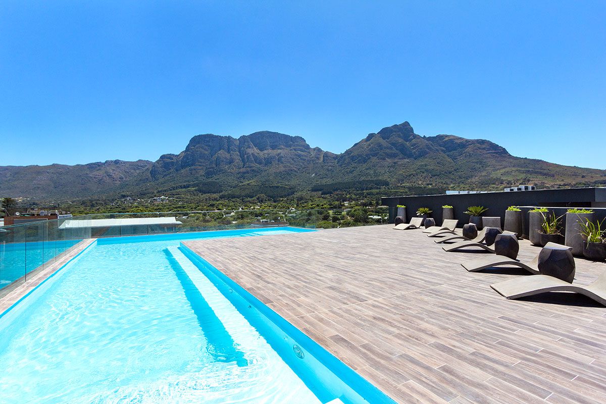 Une piscine avec vue sur les montagnes, des chaises longues et des plantes en pot.