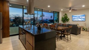 A modern kitchen with a large island, dining area with chairs, and a large window with a view.