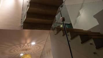 A staircase with a glass railing, a ceiling fan, and a pendant light.