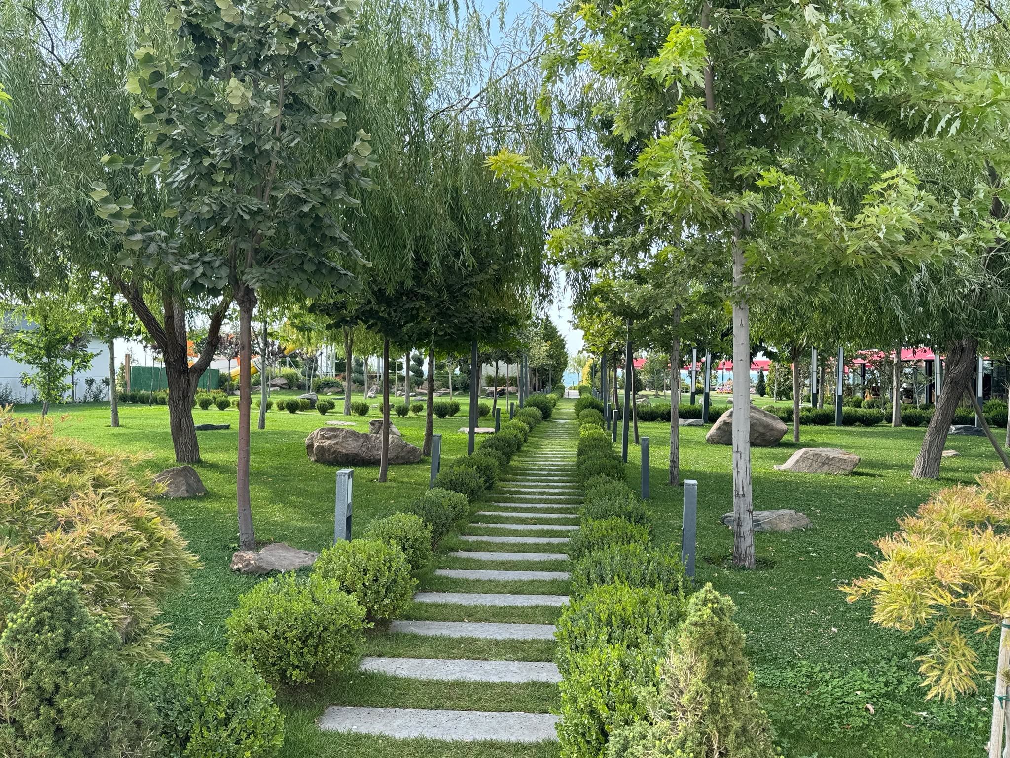 Un jardín ajardinado con un sendero de piedra, árboles y arbustos bien cuidados.