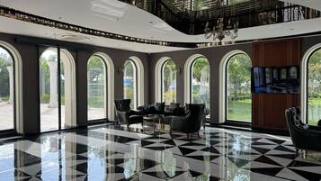 Un vestíbulo amplio con suelo de cuadros, ventanas arqueadas grandes y un candelabro.