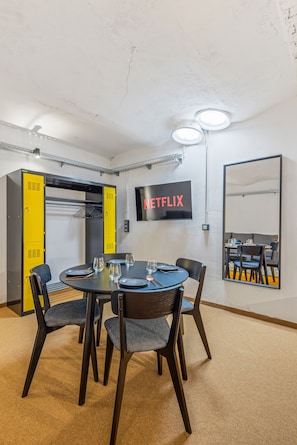 Ein Konferenzraum mit rundem Tisch, Stühlen und einem an der Wand befestigten Fernseher, der 'NETFLIX' zeigt.