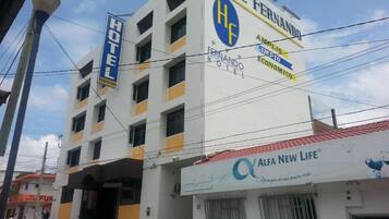 A multi-story building with a prominent 'Hotel Fernando' sign, a 'Hotel Fernandinho' sign, and a 'Alfa New Life' store.