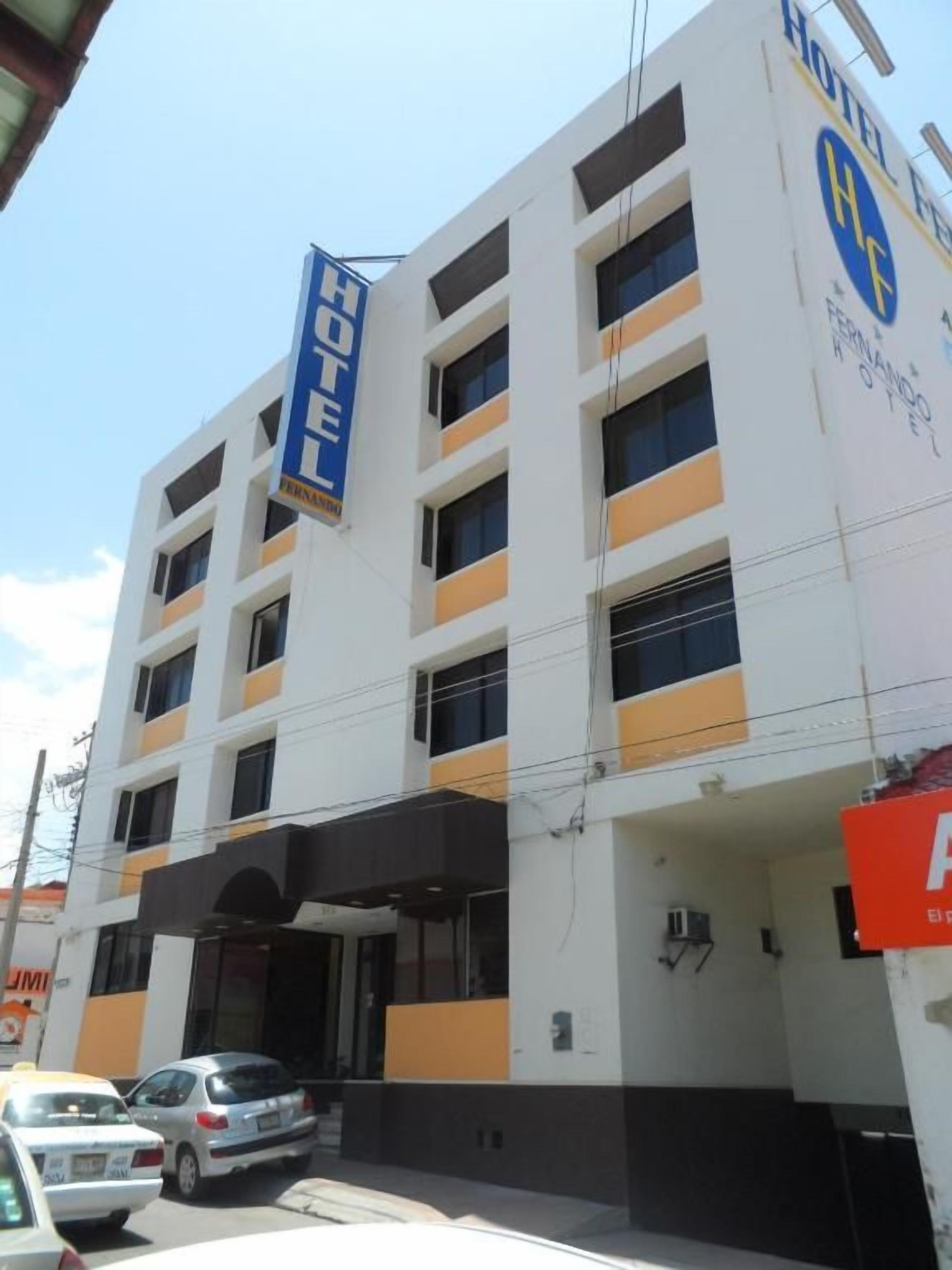 A multi-story hotel building with a prominent 'HOTEL' sign, a covered entrance, and a visible parking area.