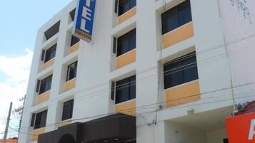 A multi-story hotel building with a prominent 'HOTEL' sign, a covered entrance, and a visible parking area.