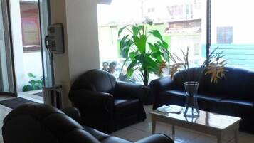 Een moderne woonkamer met een bank, fauteuils en een salontafel. Een groot raam biedt uitzicht op het omliggende landschap.