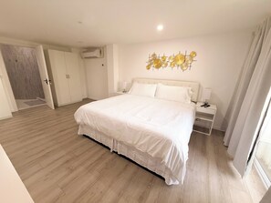 A bedroom with a large bed, bedside tables, an air conditioning unit, and a decorative wall piece. - 2-Bed Apt Downtown Walk to Beach CasaAmarilla303 (Oranjestad)