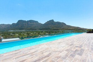 A swimming pool with a view of mountains and a tiled deck. - Newlands Peak Studio with Gym (Cape Town)