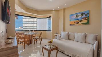 Una sala de estar con sofá, mesa de centro y comedor con sillas y una mesa dispuesta para dos.