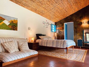 Een kamer met een bed, een bank, een televisie en een schilderij aan de muur.