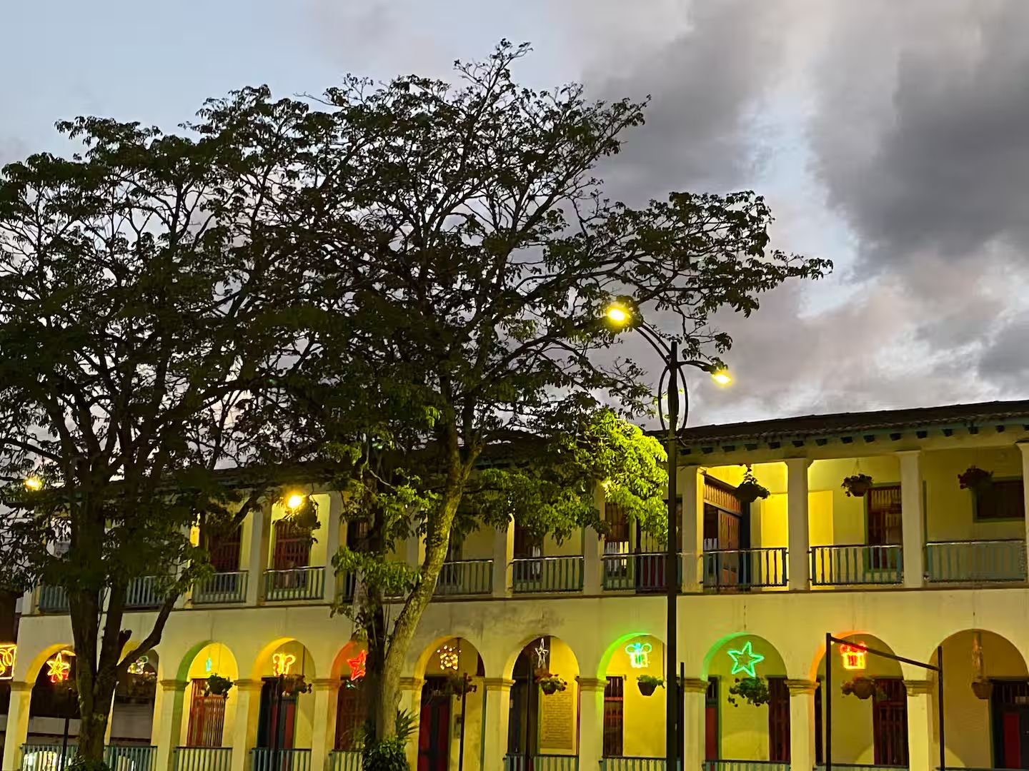 A building with multiple balconies, arched windows, and hanging plants.