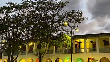 A building with multiple balconies, arched windows, and hanging plants.