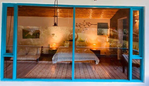 A room with a bed, a nightstand, a lamp, and a wall-mounted artwork.