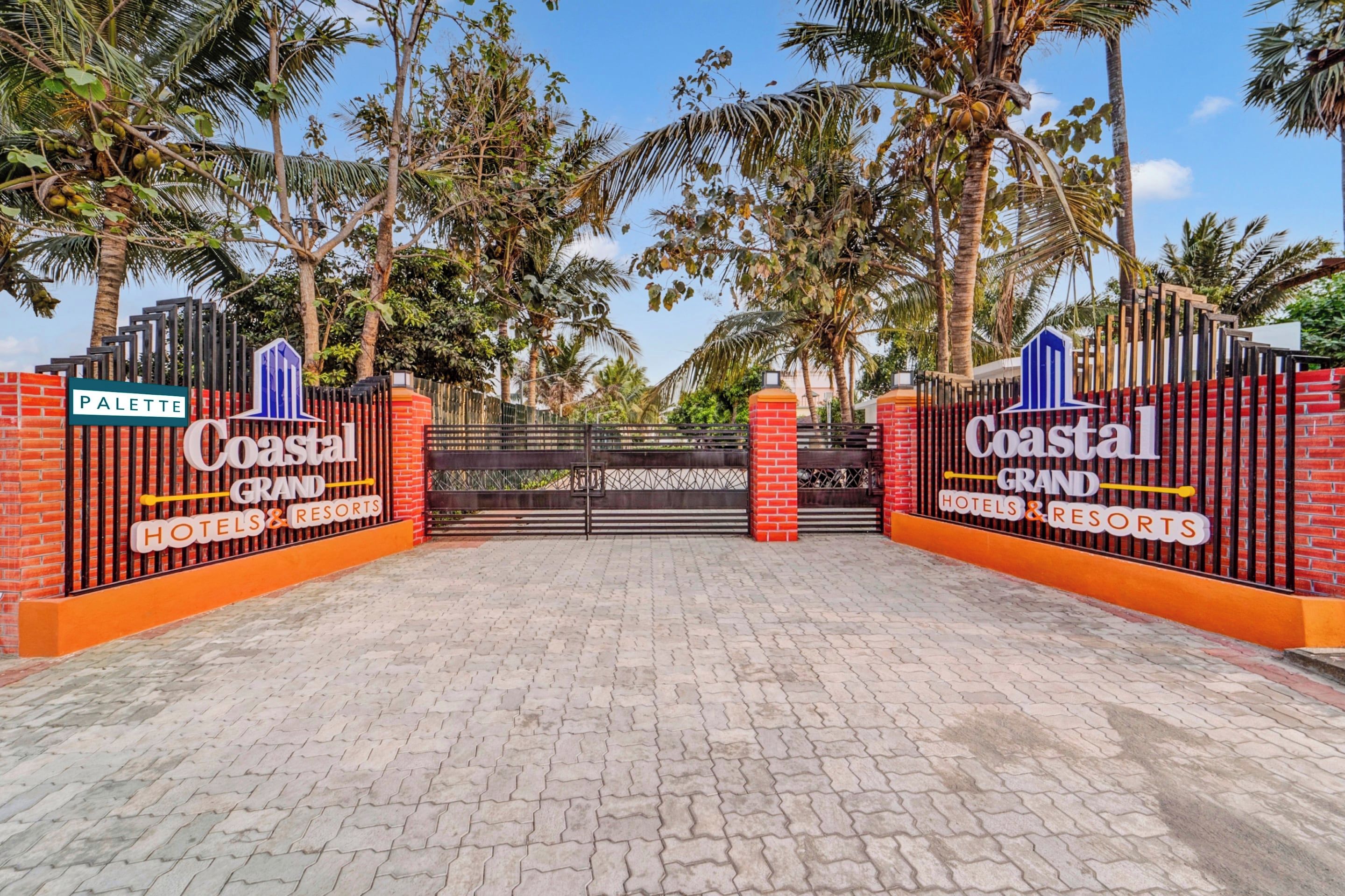Una entrada con reja a Coastal Grand Hotels & Resorts, con un camino pavimentado que se interna.