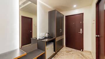 A hotel room with a marble floor, a minibar, a wardrobe, and two doors.