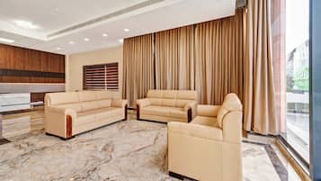 A modern living room with a sofa set, a coffee table, and a large window with curtains.