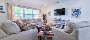 A living room with a sofa, a coffee table, a TV, and a bookshelf. - Hog Plum 3-bedroom 2 minute walk to the beach with Kayak and paddle board (Spanish Wells)