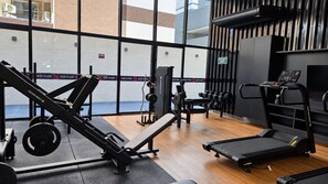 A gym with exercise equipment, a treadmill, and a window with a view of buildings. - Estúdio aconchegante de 1 quarto com ar-condicionado na maravilhosa Maceió. (Maceió)