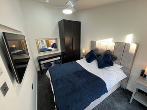 Ein Hotelzimmer mit Bett, Nachttisch, Lampe, Kleiderschrank und Spiegel.