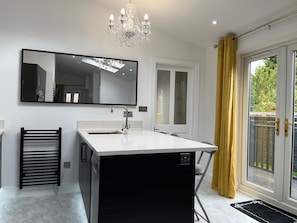 A modern bathroom with a large mirror, a black sink, and a chandelier. - House Sleeps 4 - Private Garden - Bbq (York)