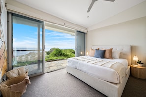 A bedroom with a large bed, a nightstand, a lamp, and a view of the outdoors. - Elysian Allure Oceanfront Paradise with Pool and Spa (Normanville)