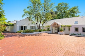 A building with a brick driveway, white exterior walls, and a covered entrance. - Raithbury Hill House (Stellenbosch)