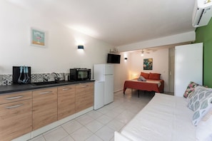 A compact kitchen with a microwave, refrigerator, and wooden cabinets. - Air-conditioned studio with a terrace and pool, 5 minutes from the beaches of Sainte-Anne (Sainte-Anne)