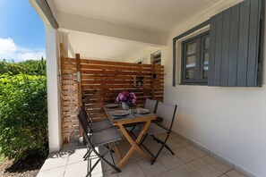 An outdoor dining area with a wooden table and chairs, a potted plant, and a view of greenery. - Air-conditioned studio with a terrace and pool, 5 minutes from the beaches of Sainte-Anne (Sainte-Anne)